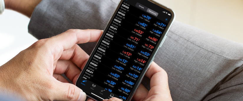 A person using a mobile phone to monitor stock market trading data and graphs.