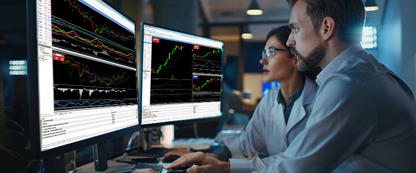 Two people engaged with computer screens displaying trading data, highlighting the psychological aspects of market analysis.