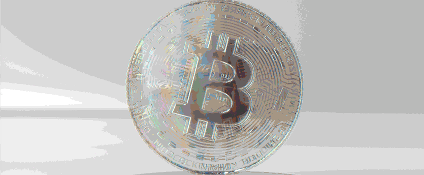 A close-up of a silver Bitcoin physical token standing upright against a bright, minimalist background, ideal for breaking crypto news bitcoin ethereum market announcements.